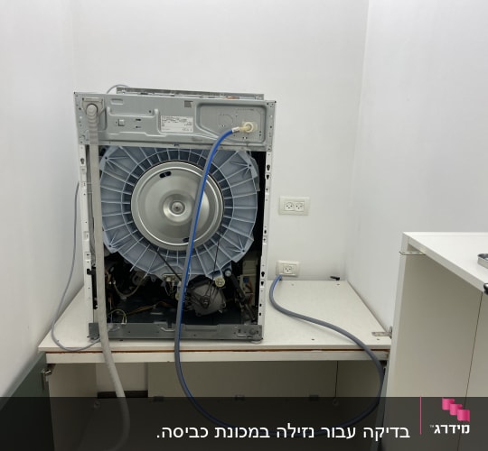 מכונת כביסה פתוחה עם חיבורים חשמליים וצינורות